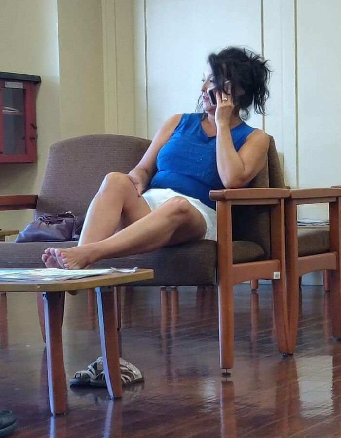 Woman sitting in a waiting room with feet on table, on her phone; exemplifying inconsiderate behavior.