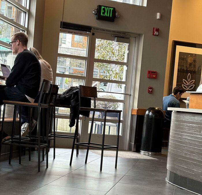 People being inconsiderate, blocking an exit at a cafe while using laptops.