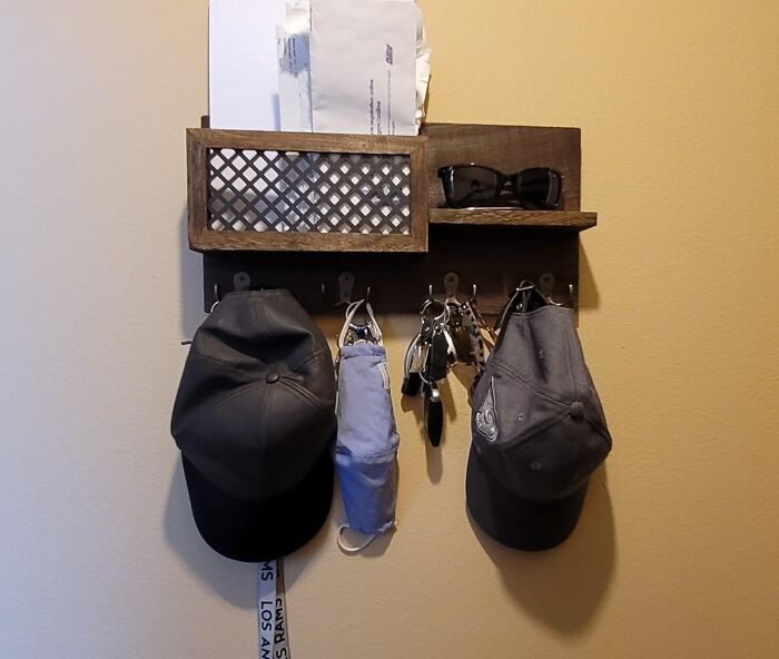 Wall-mounted organizer for renter friendly upgrades, holding hats, keys, sunglasses, and mail against a beige wall.