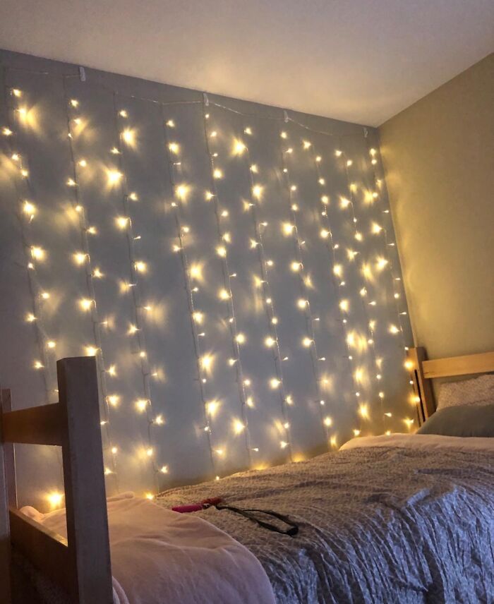 Fairy lights on a bedroom wall create a cozy and renter friendly upgrade.