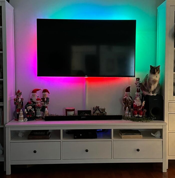 TV with colorful LED backlighting and holiday decor on shelves; a cat sits on a speaker. Ideal renter-friendly upgrades.