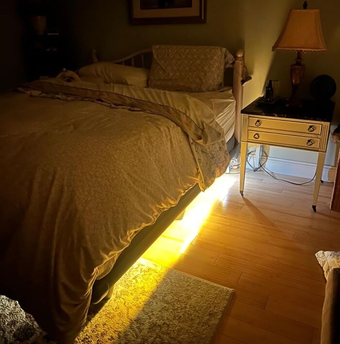 Cozy bedroom with warm lighting, featuring a bed, side table, and lamp; ideal setting for renter-friendly upgrades.