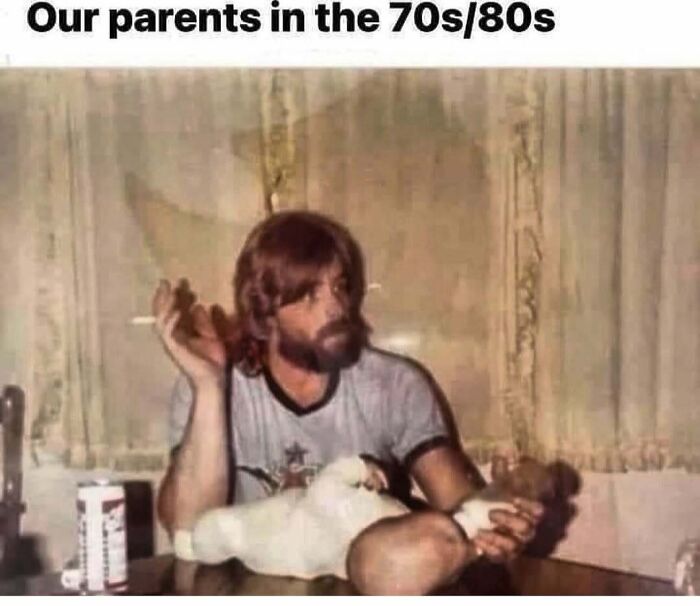 Nostalgic meme of a man in the 70s/80s with a beard, holding a baby, and smoking, with a retro hairstyle and decor.