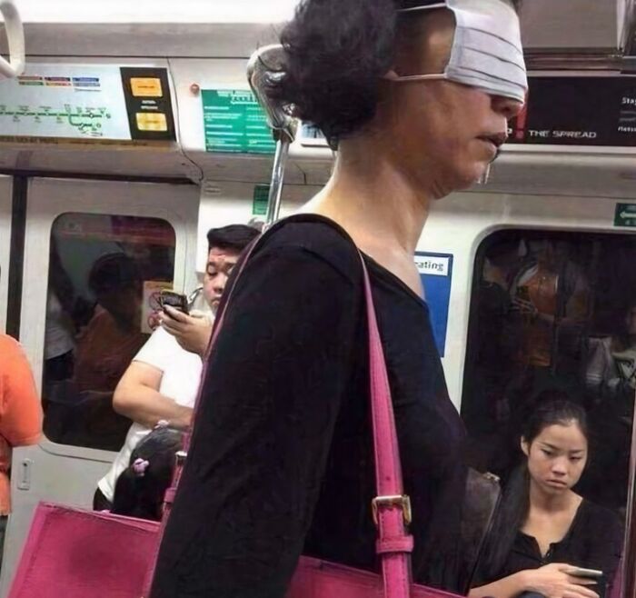 Funny train subway passenger with sunglasses and a pink bag, attracting attention from others in the carriage.