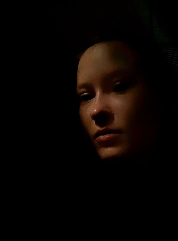 Dimly lit face resembling a Renaissance painting with dramatic shadows.