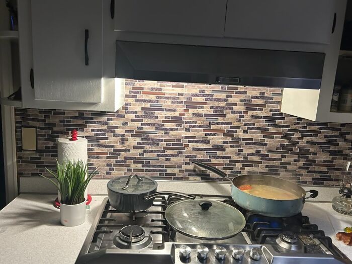 Modern kitchen with mosaic backsplash and stovetop cooking, enhancing your apartment's style.