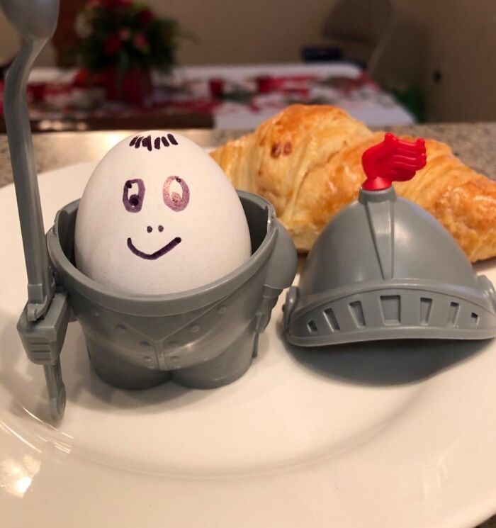 Egg dressed as a knight in armor, next to a croissant, illustrating weirdest gift ideas for friends.