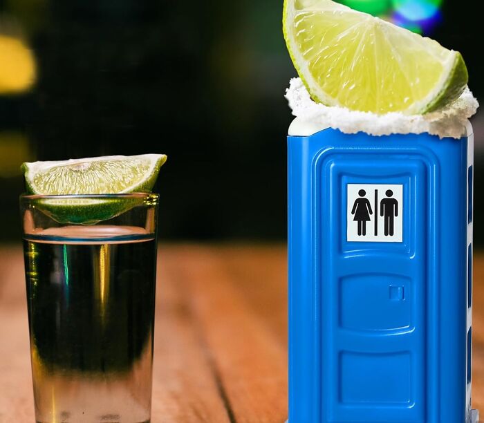 Weirdest gifts: Blue porta-potty shooter with salt and lime beside a shot glass with lime on a wooden table.