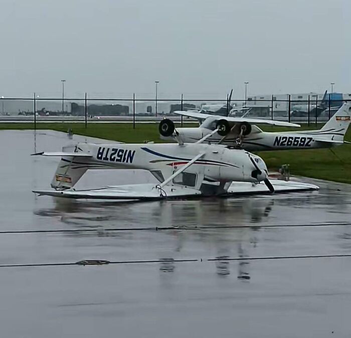 Small aircraft tipped over on wet tarmac at an airport, reflecting an unfortunate incident likely costing a fortune.