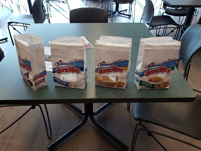 Company gifts include four bags of Hostess Donettes on a table.