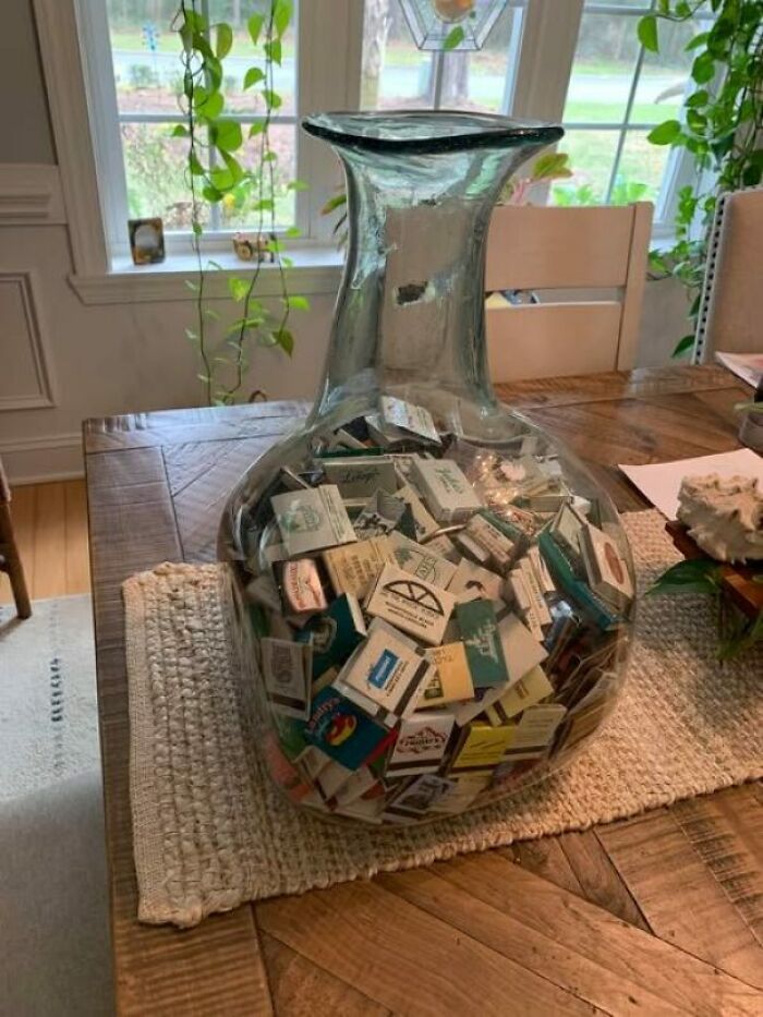 Glass vase filled with matchbooks on a wooden table, showcasing a unique secondhand find.