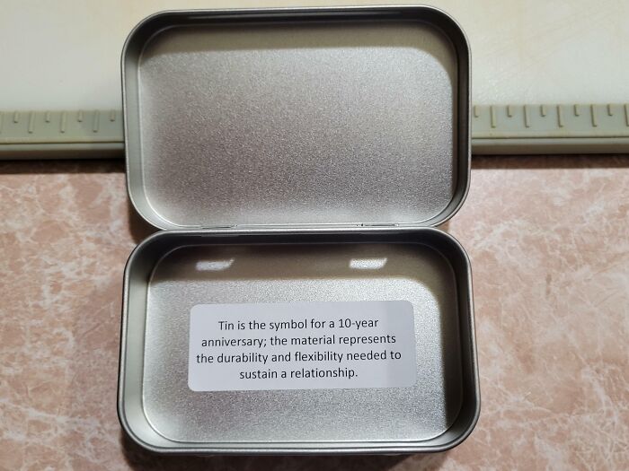 Open tin box with message about anniversaries, symbolizing infuriating company gifts bonuses.