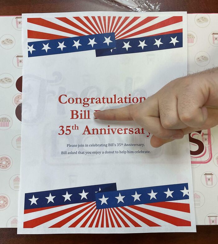 Finger pointing at a company anniversary note about gifts and bonuses on a decorated paper.