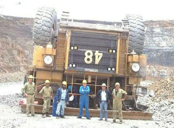 Workers standing next to an overturned mining truck, illustrating an unfortunate incident that looks expensive.