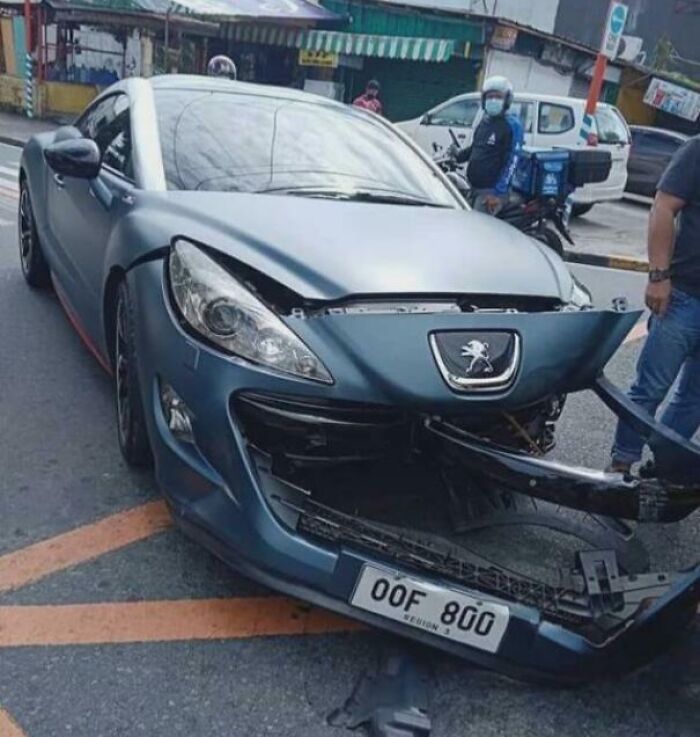 Damaged Peugeot car involved in an unfortunate incident, with a broken front bumper on a street.