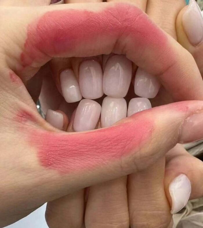 Hands creating a lip shape with lipstick outline, showcasing bizarre creativity.