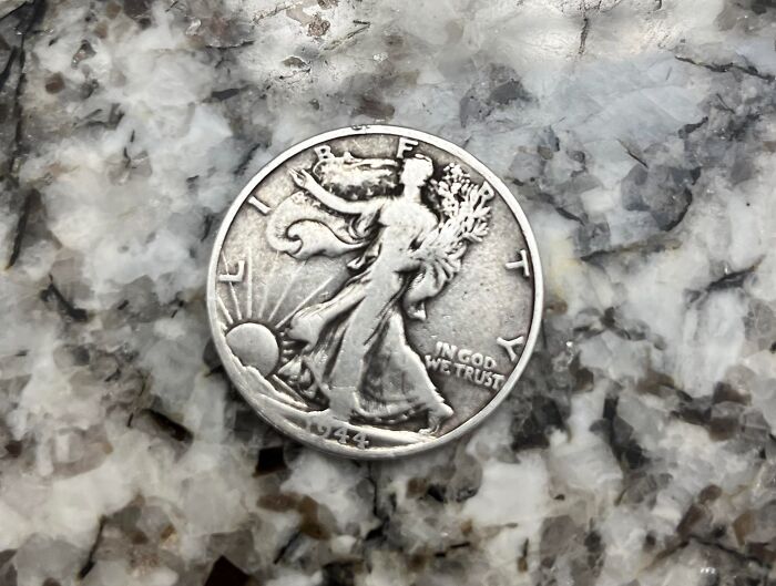 A vintage coin with "Liberty" inscription, lying on a marble surface, appealing to numismatists.