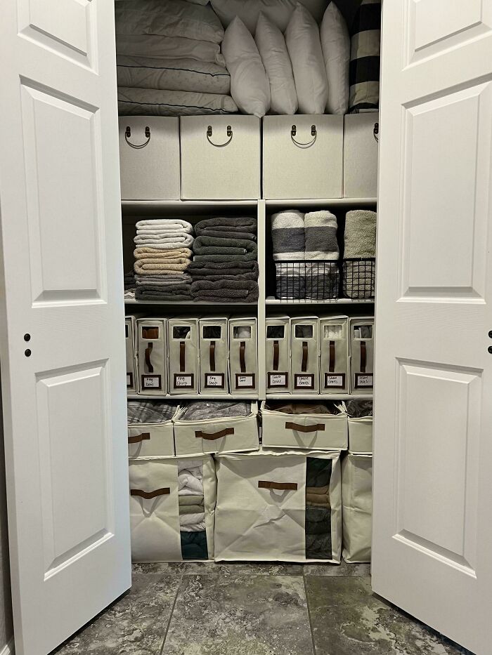 Closet with next-level organization featuring neatly stacked linens, pillows, and labeled storage bins.