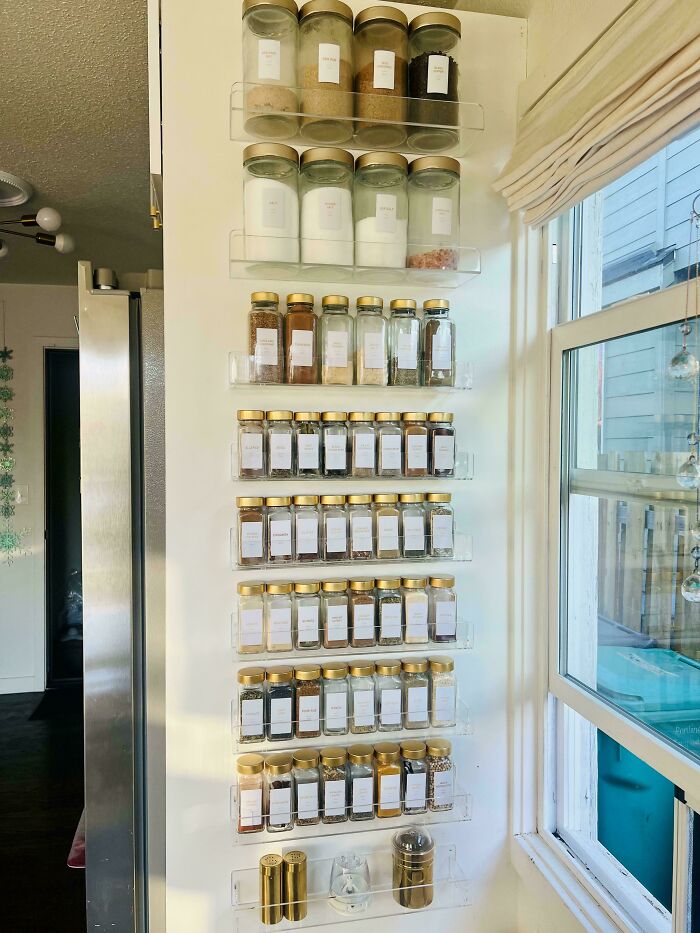 Wall-mounted spice rack with jars neatly organized in a kitchen, showcasing next-level organization skills.