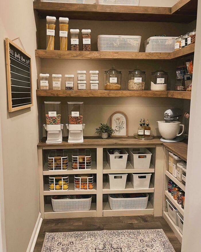 Neat pantry organization with labeled containers and baskets on wooden shelves.