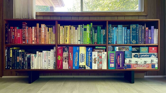 Color-coordinated bookshelf showcasing next-level organization with books and board games neatly arranged.