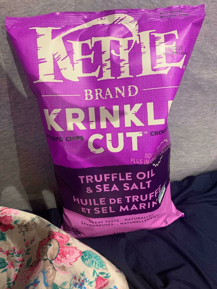 Bag of Kettle Brand Krinkle Cut chips, truffle oil, and sea salt flavor, on a floral and dark fabric background.