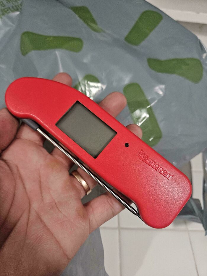 Hand holding a red thermapen, possibly from a lifetime supply experience winner.