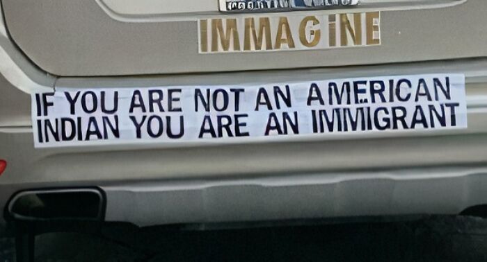 Bumper sticker with humorous message on a car, discussing immigration.