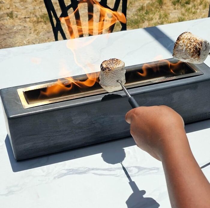 Roasting marshmallows over a sleek tabletop fire pit, showcasing cool products.