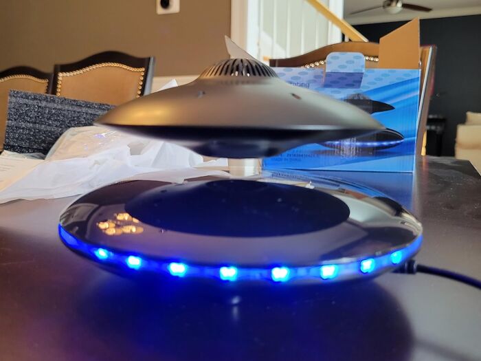 Levitating speaker with blue LED lights on display table, perfect for showoffs.