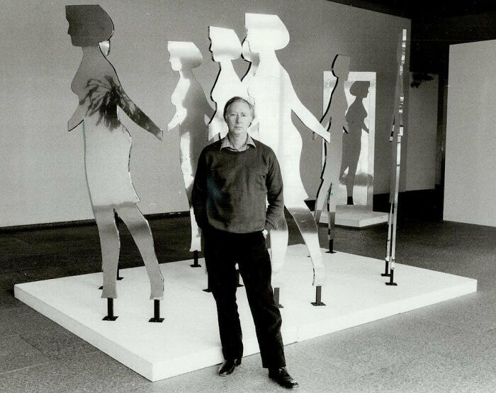 Man standing among impressive woodworking projects featuring cutout figures.