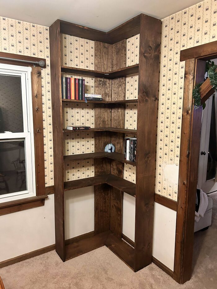 Corner bookshelf showcasing impressive woodworking projects with books on display.