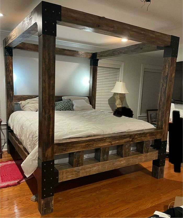 Canopy bed made from dark wood in a modern bedroom, showcasing impressive woodworking craftsmanship.