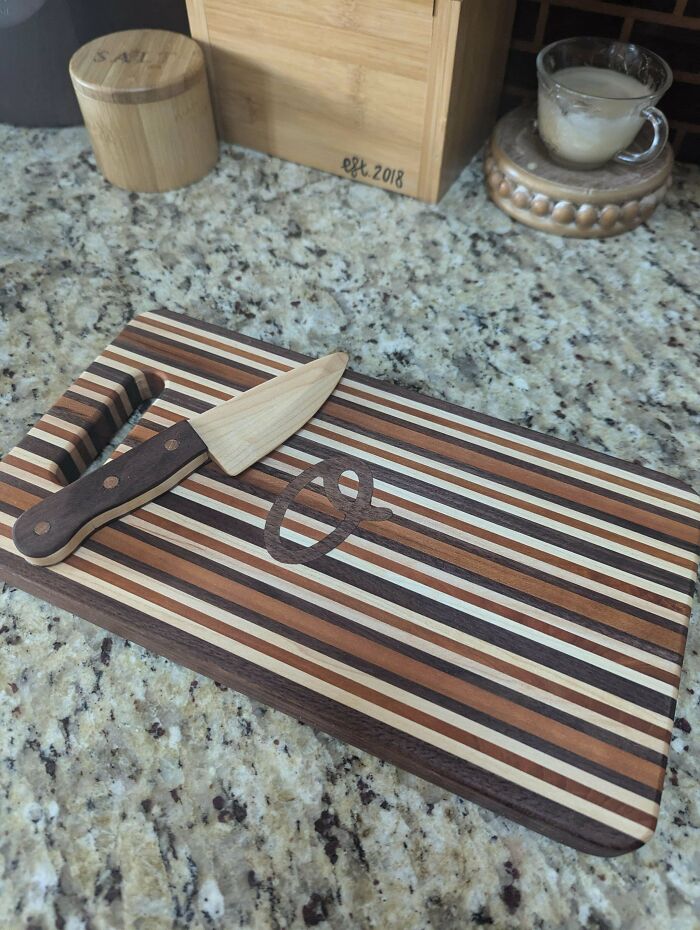 Striped wooden cutting board with matching wooden knife on a granite countertop, showcasing impressive woodworking projects.