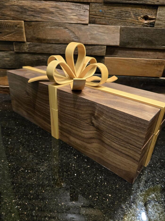 Woodworking project featuring a polished wooden gift box with a decorative bow on a textured wood backdrop.