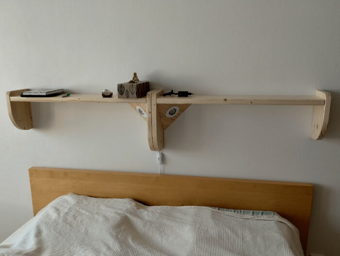 Woodworking project showcasing a unique wooden shelf above a bed, holding books and decor items.