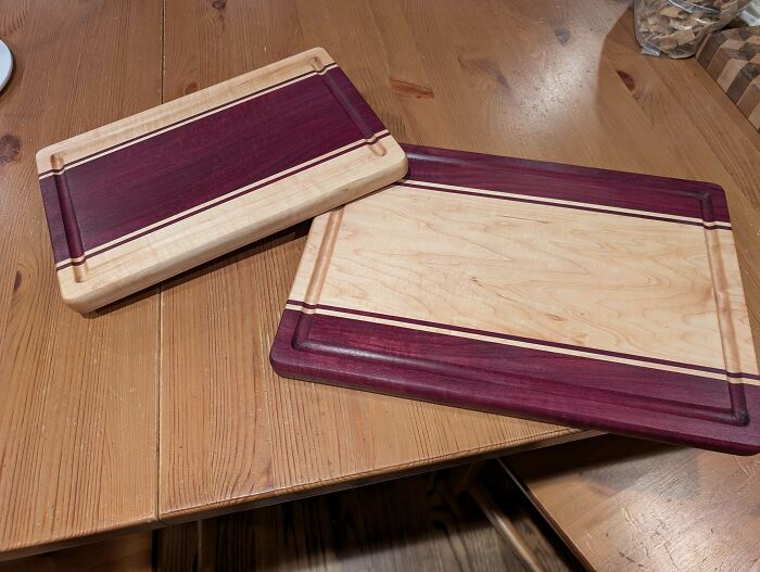 Woodworking project featuring two handcrafted cutting boards with purpleheart and maple wood on a wooden table.