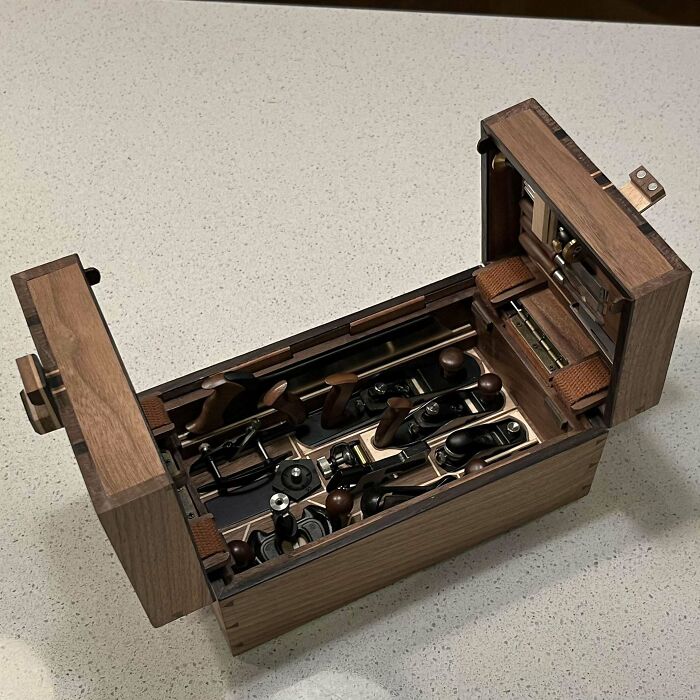 Intricate woodworking project featuring a detailed wooden toolbox with various tools displayed on a countertop.