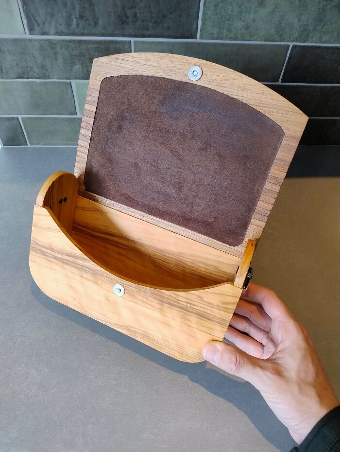 Hand holding a wooden box with a hinged lid, showcasing impressive woodworking craftsmanship.