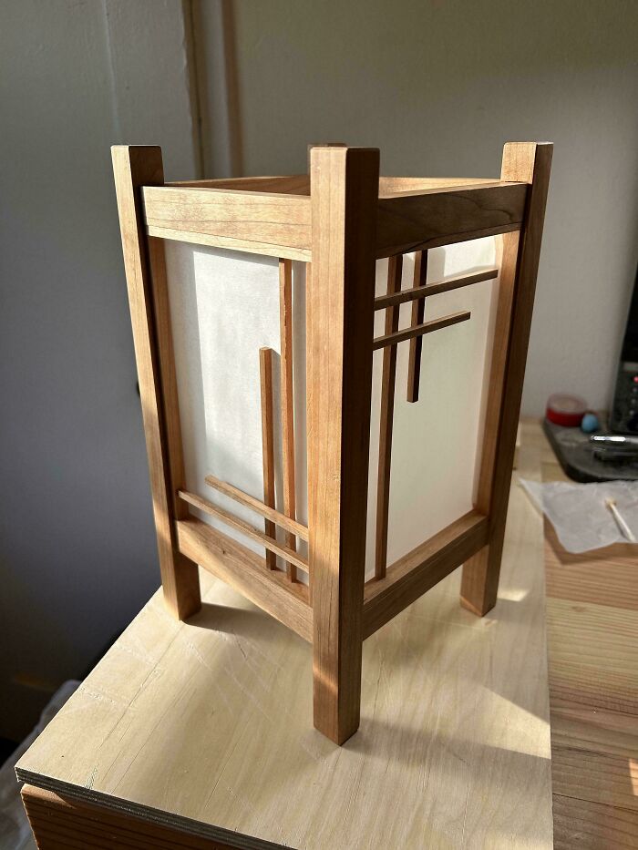 Woodworking project featuring a wooden lamp with geometric design, highlighting craftsmanship and attention to detail.