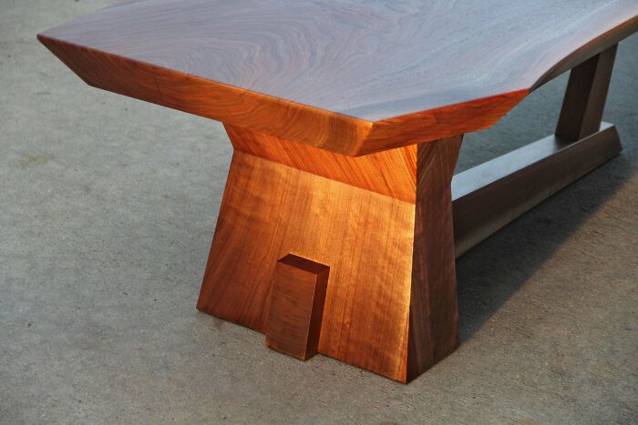 Woodworking project showcasing a polished wooden table with geometric design on a concrete floor.