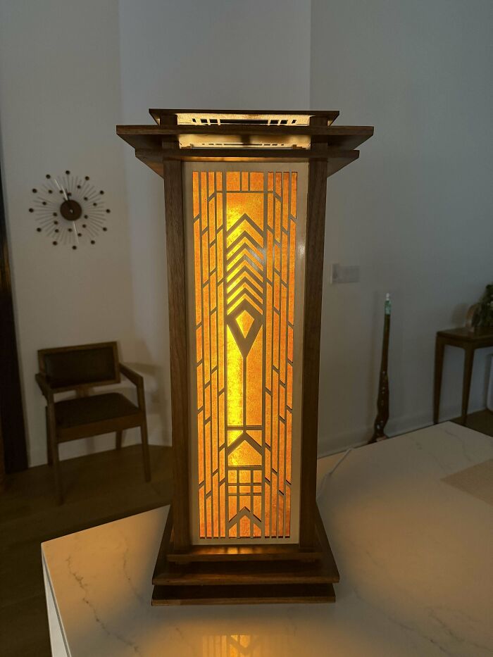 Woodworking project featuring a glowing geometric wooden lamp with intricate design on a table.