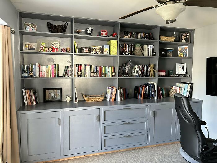 Gray custom-built bookshelf filled with books and decorative items, a fine example of impressive woodworking projects.