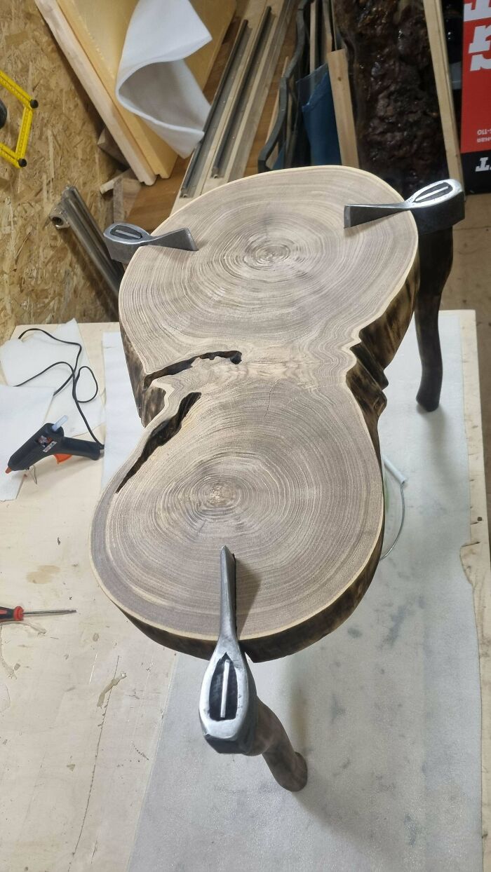 Natural wood table with metal legs, showcasing impressive woodworking craftsmanship in a workshop setting.