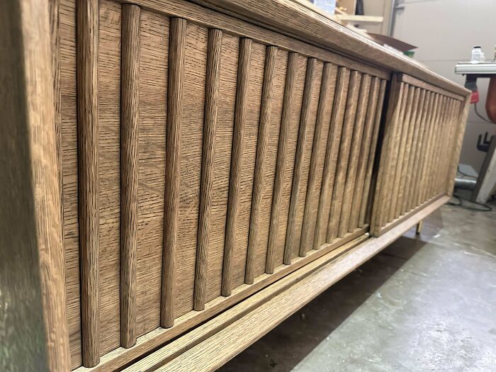 Woodworking project showcasing a detailed wooden cabinet with vertical slats in a workshop setting.