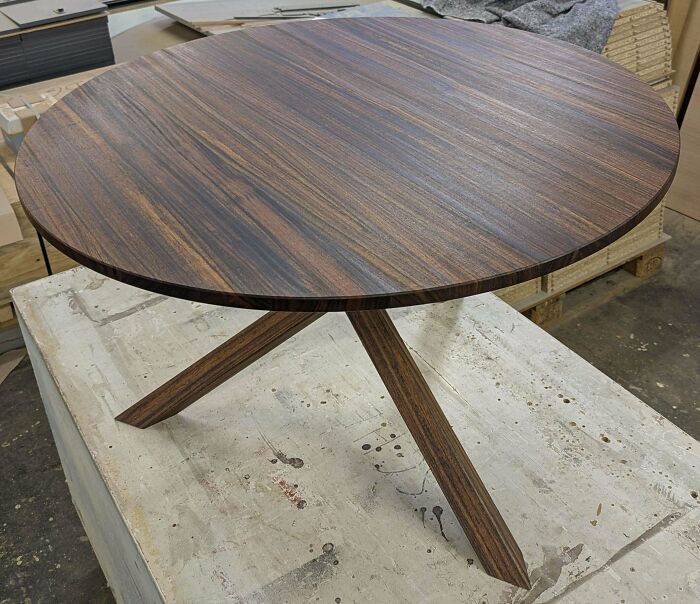 Round wooden table with cross-legged base, showcasing impressive woodworking craftsmanship.