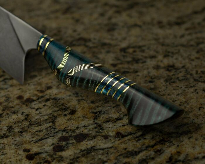 Handcrafted knife handle showcasing intricate woodworking on a stone surface.