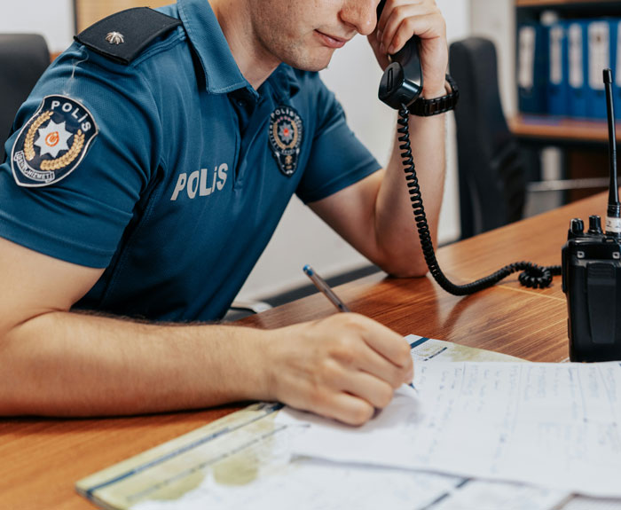 Police officer on the phone taking notes in an office setting.