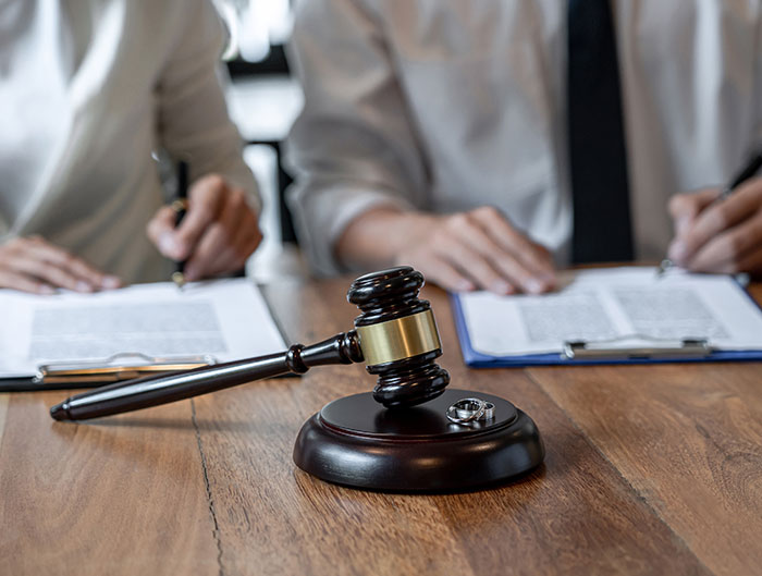 Legal paperwork with a gavel and wedding rings, highlighting a scam involving a bride and influencer.