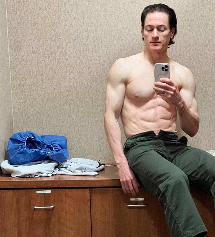 A man taking a mirror selfie, sitting shirtless on a dresser, with a focus on reversing aging.